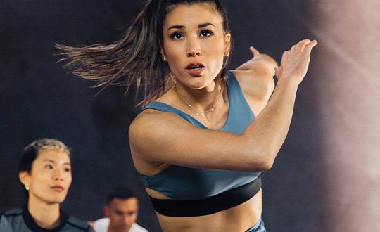 Four people doing box jumps onto black boxes in PEAK training space