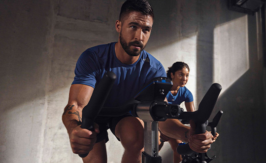 Woman in purple long-sleeved shirt trains on stationary bicycle