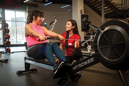 GoodLife Fitness trainer observes a client doing an exercise with medicine ball