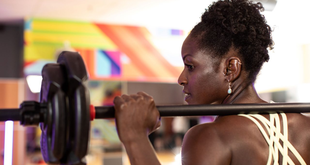 Woman holding barbell on shoulders and looking to the left 