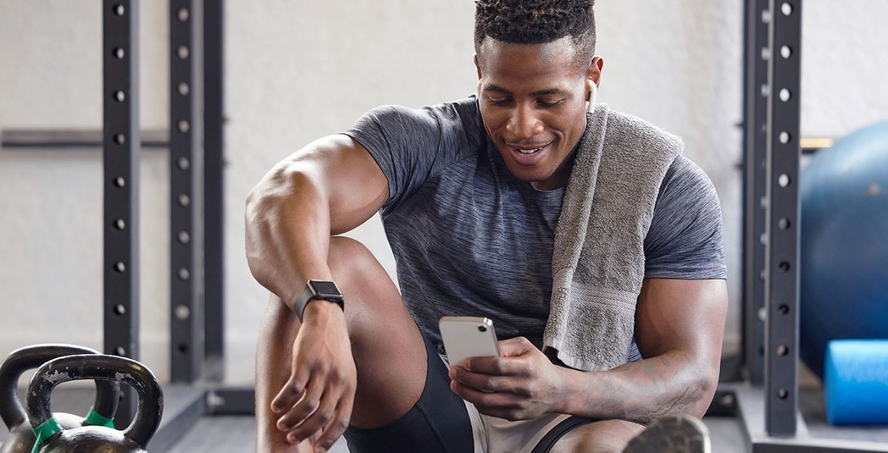 Man sitting in a gym looking at his mobile phone