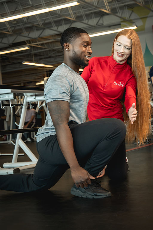 A GoodLife Fitness Personal Trainer directing a member who is stretching.