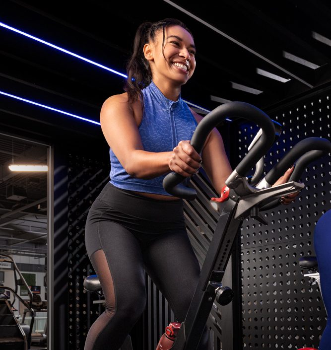 Woman in purple long-sleeved shirt trains on stationary bicycle